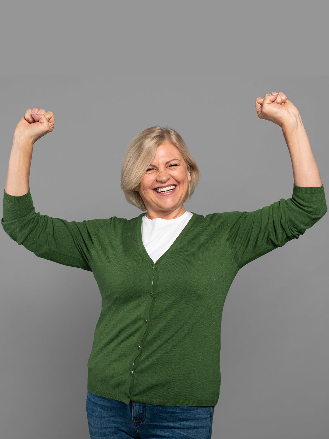 happy senior woman in green sweater raising arms in joy