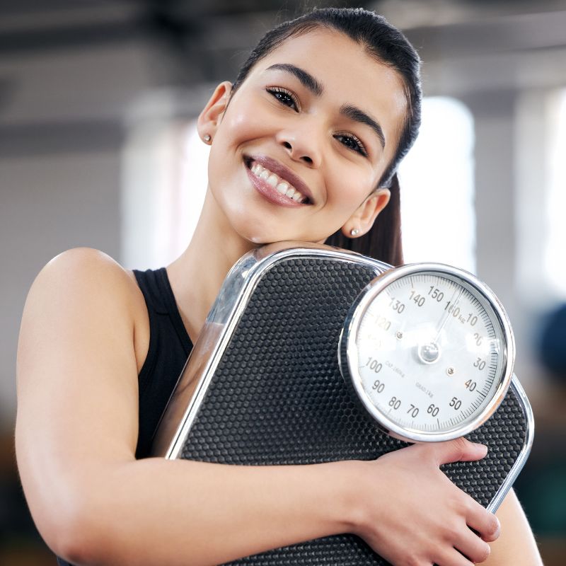 Happy woman holding scale showing weight loss